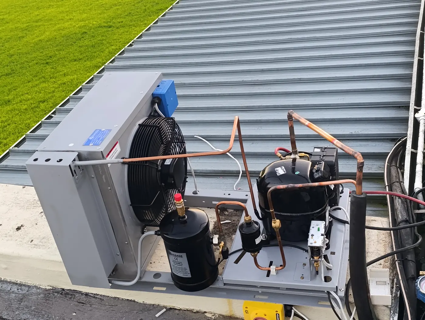 Close-up of a commercial refrigeration condensing unit with compressor and copper pipework