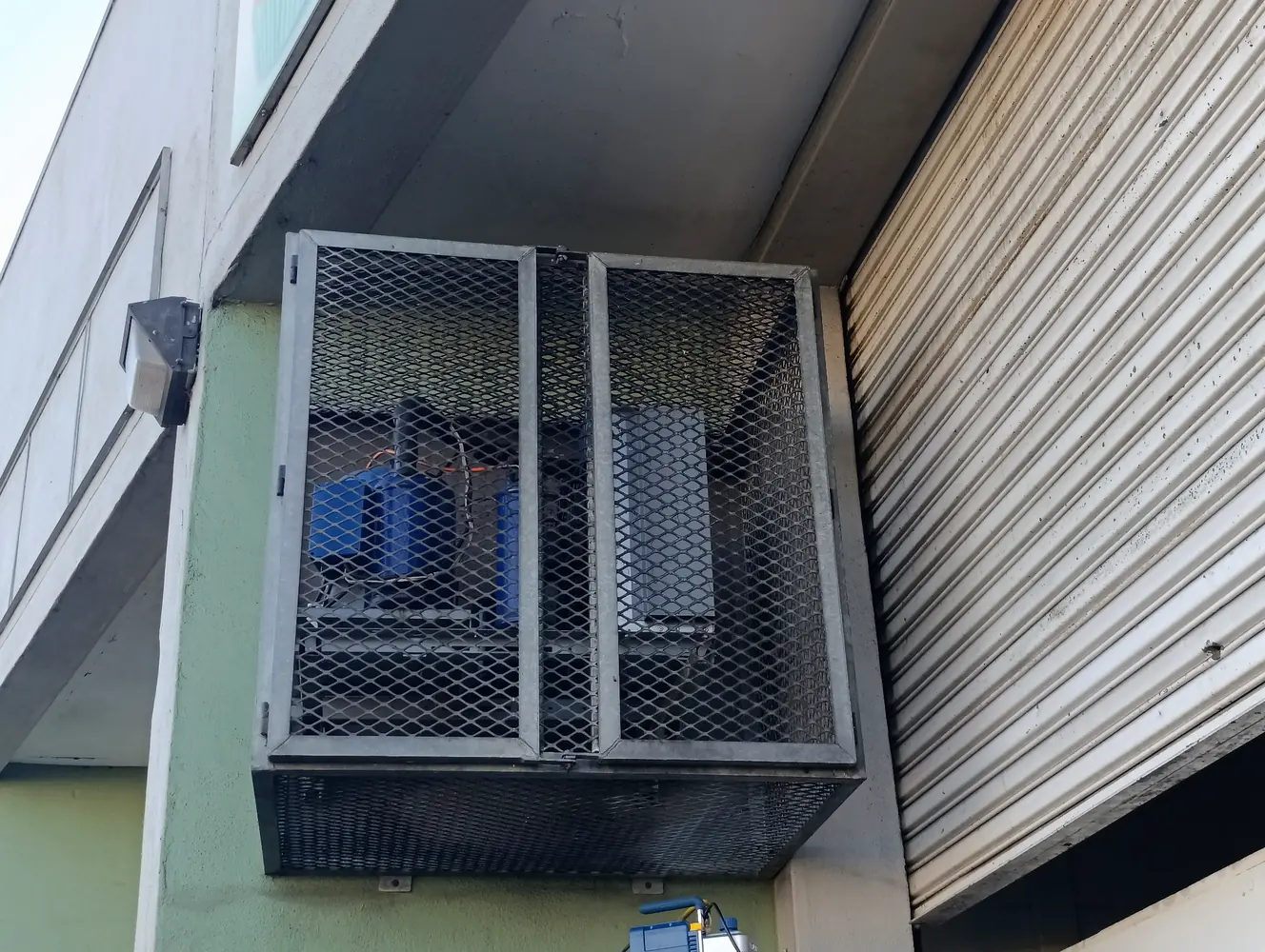 Outdoor commercial refrigeration condensing unit installed in a secure metal cage