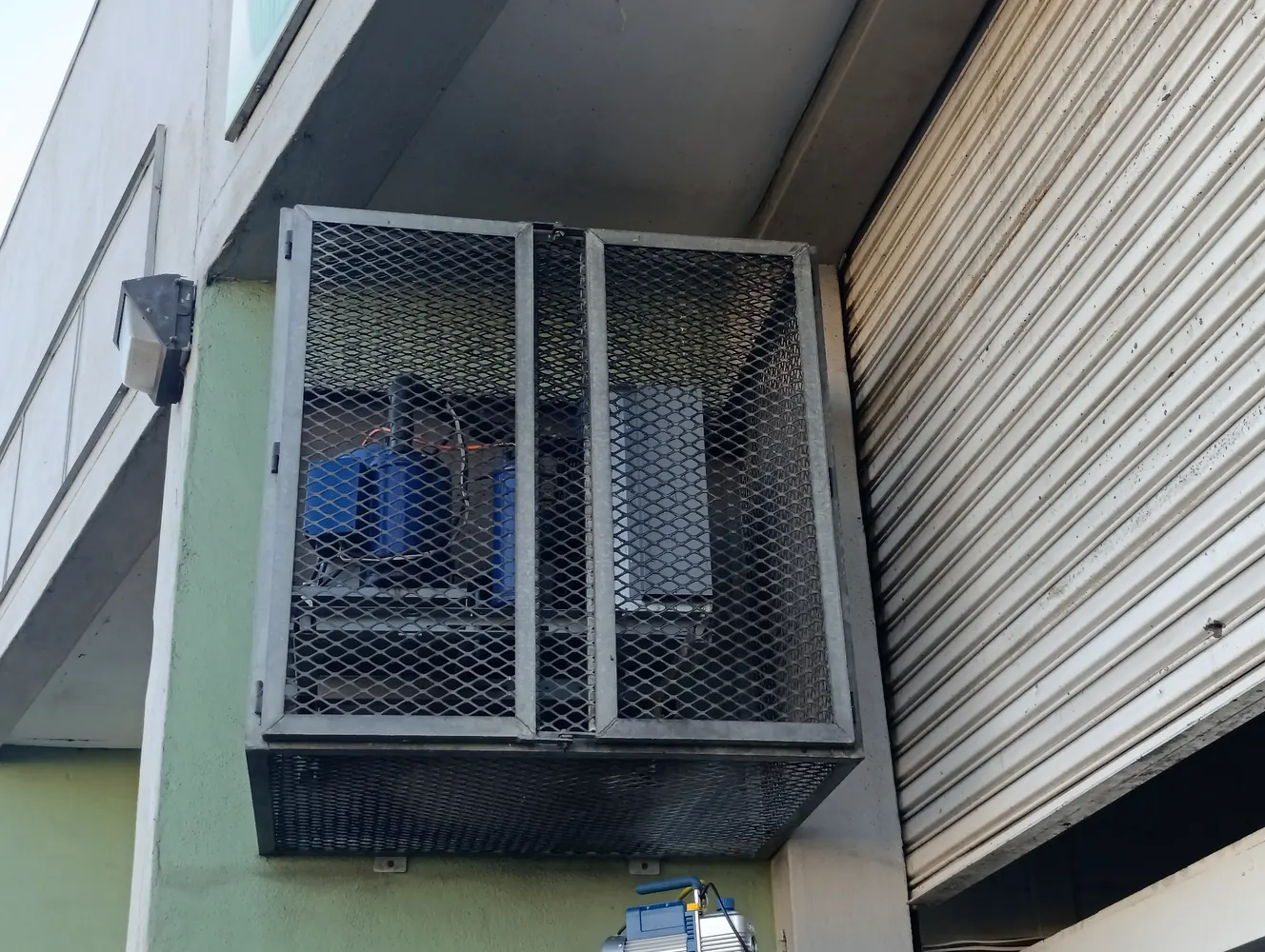 Commercial refrigeration condensing unit protected inside a metal security cage
