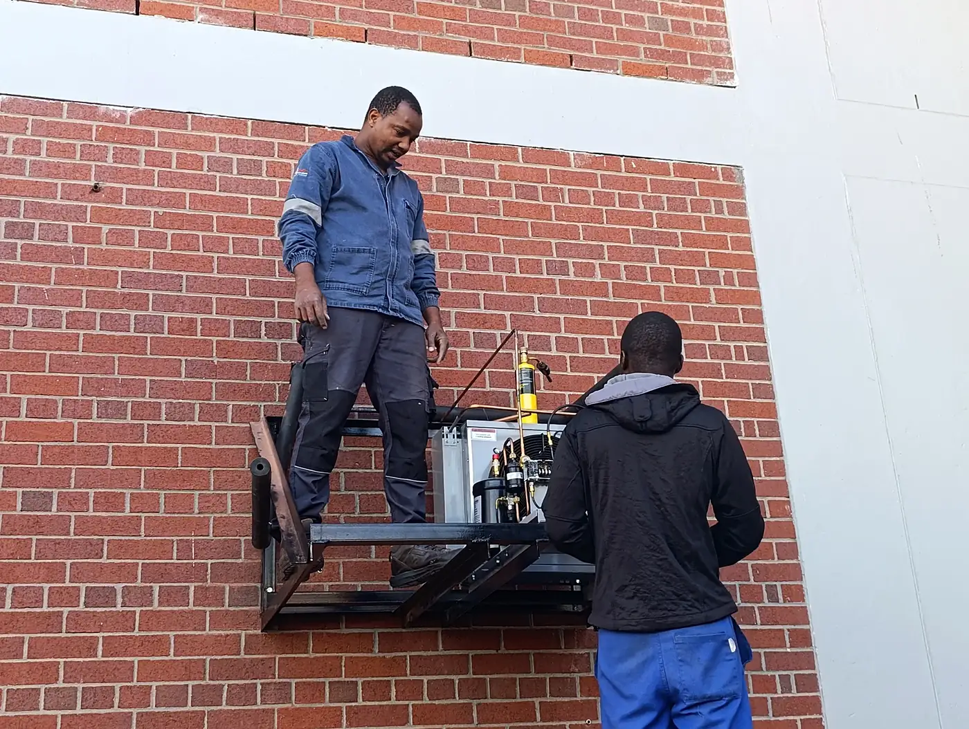 Refrigeration technicians installing a condensing unit at Sable Square in Milnerton