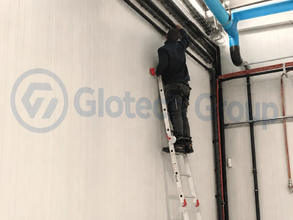 Technician installing overhead refrigeration pipework inside a commercial cold storage facility