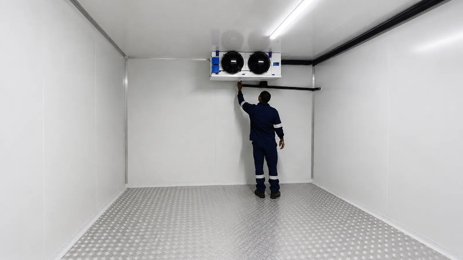 Refrigeration technician inspecting the evaporator inside the walk-in freezer